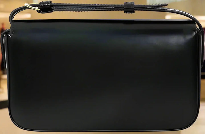 Black leather handbag with a strap on a white background