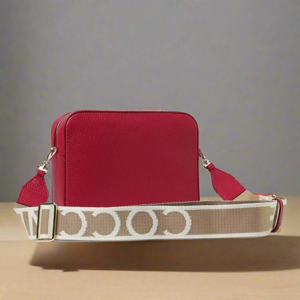 Red handbag with a beige and white patterned strap on a white background