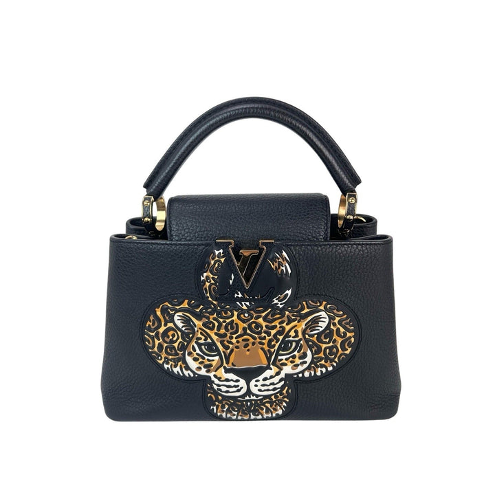 Black handbag with a leopard design and gold accents on a white background