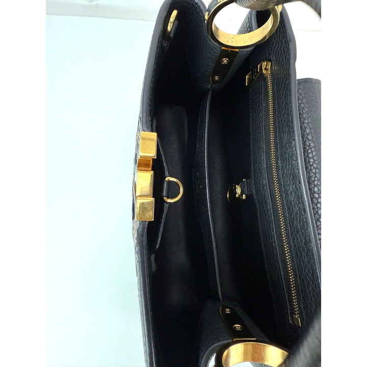 Black handbag with gold hardware on a light blue background