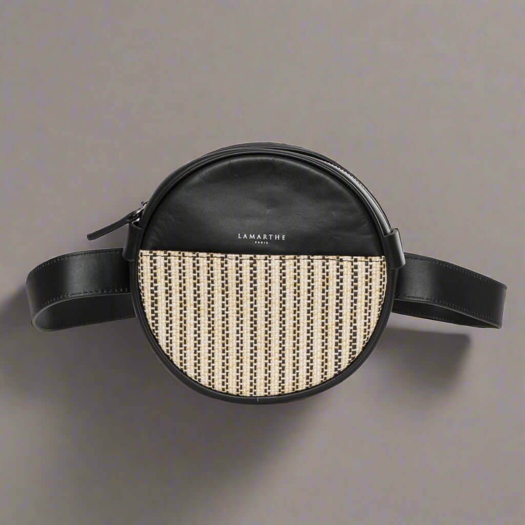 Round black leather bag with woven pattern on a white background