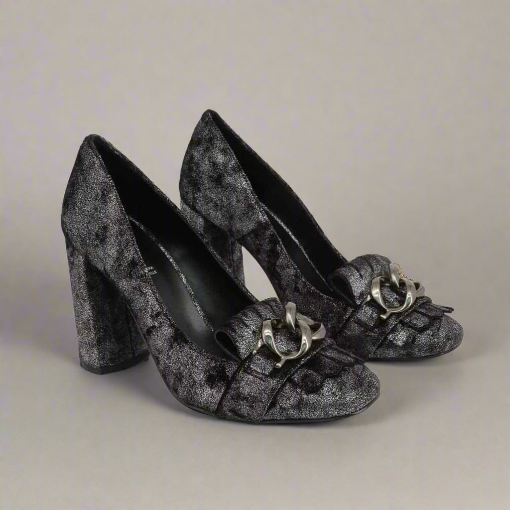 Pair of black high-heeled shoes with decorative elements on a light gray background