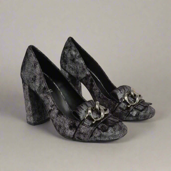 Pair of black high-heeled shoes with decorative elements on a light gray background
