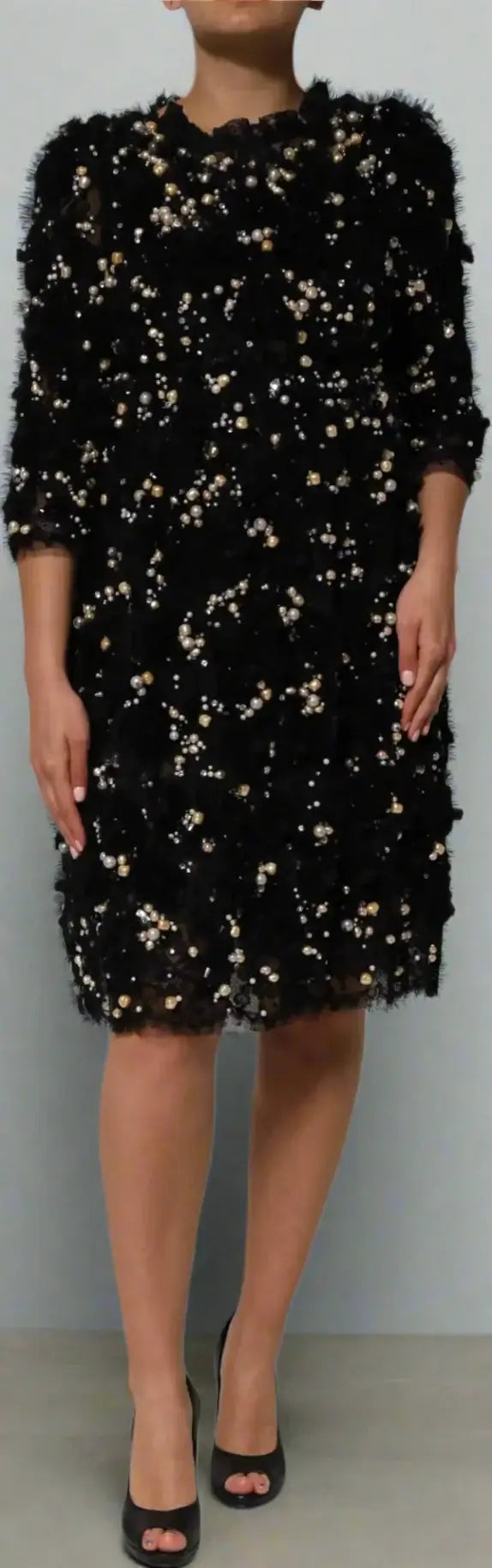 Black sequin dress worn by a model on a white background