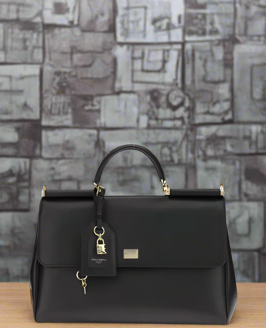 Black handbag with gold accents on a light gray background