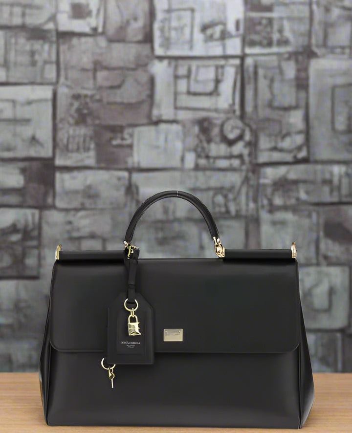 Black handbag with gold accents on a light gray background