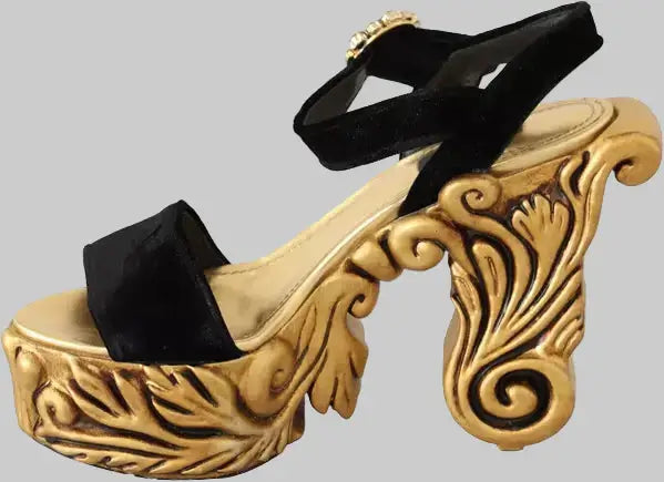 Gold high-heeled shoe with black ribbon on a white background