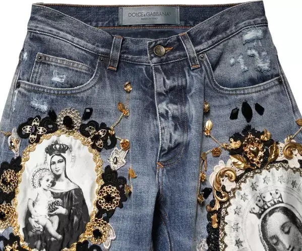 Decorative jeans with embellishments and religious-themed designs on a white background