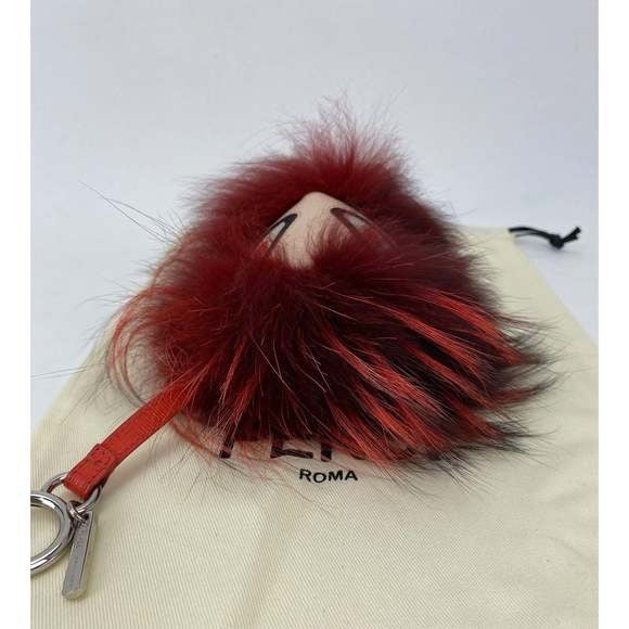 Red fluffy keychain with a face on a beige surface