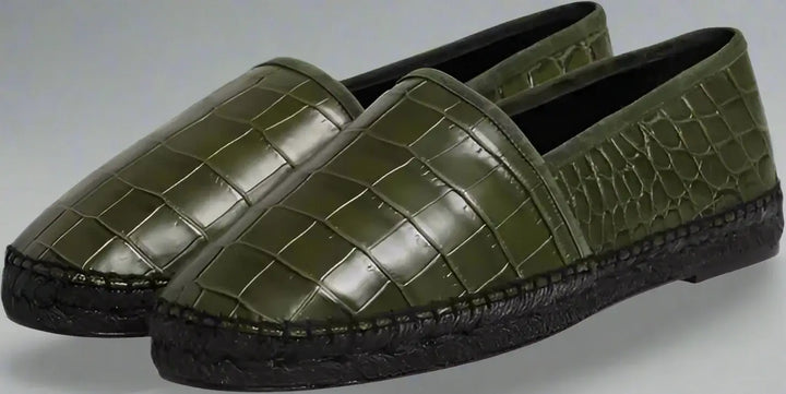 Pair of green crocodile-patterned loafers on a white background