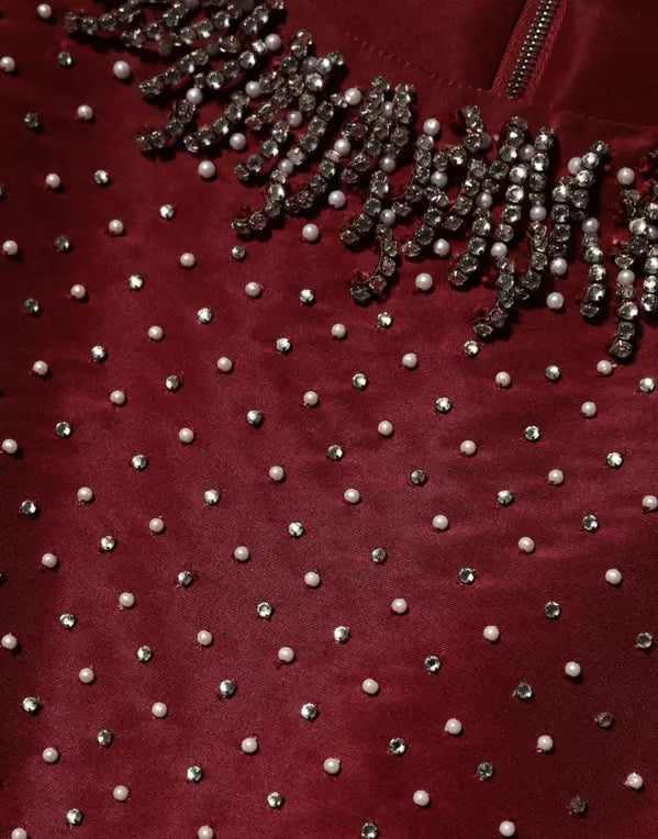 Close-up of a red garment with pearl embellishments
