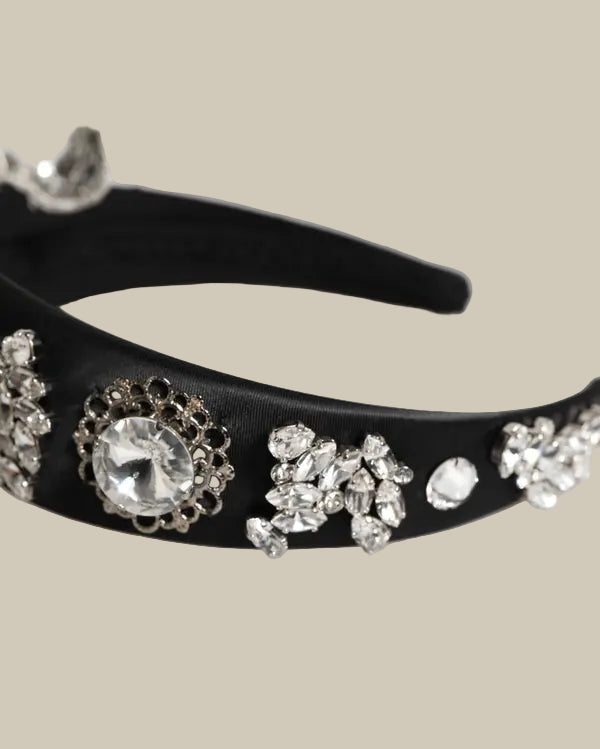 Black headband with decorative crystals on a white background