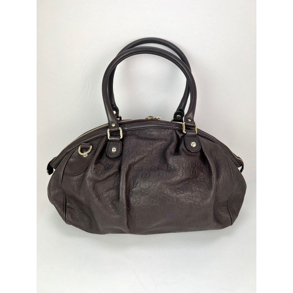 Brown handbag with gold accents on a light gray background