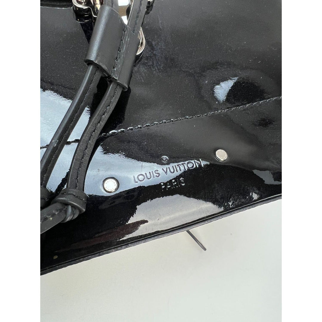 Close-up of LOUIS VUITTON Hot Springs Backpack White Monogram and Patent Leather, showcasing logo and shiny patent finish.