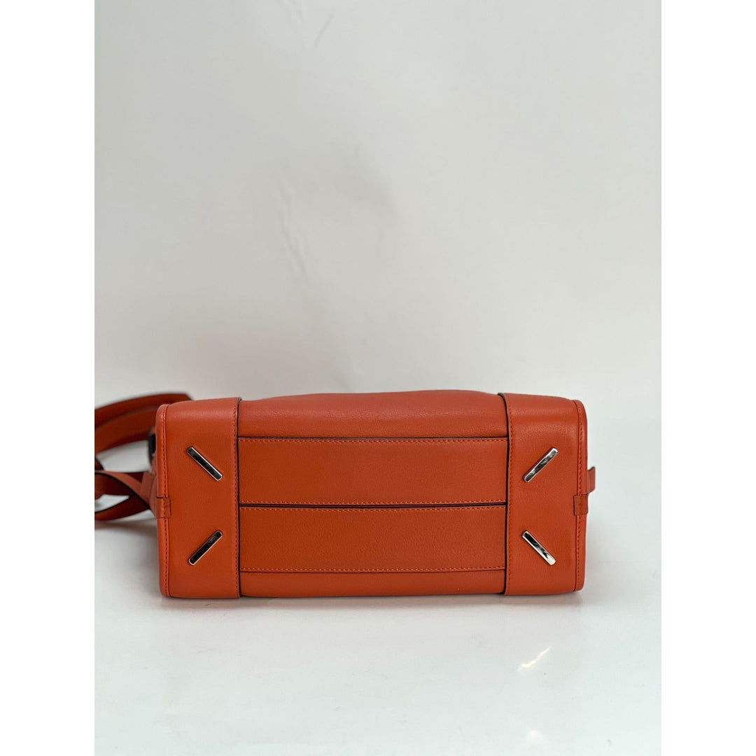 Brown leather handbag with silver accents on a light gray background