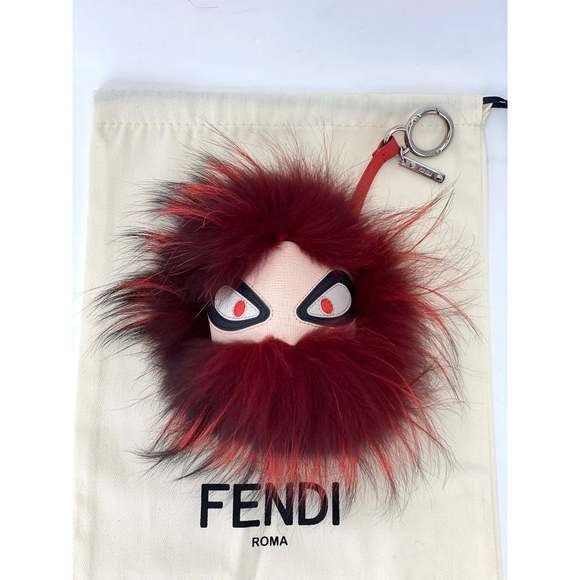 Fendi keychain with red fur and white face on a branded Fendi pouch.