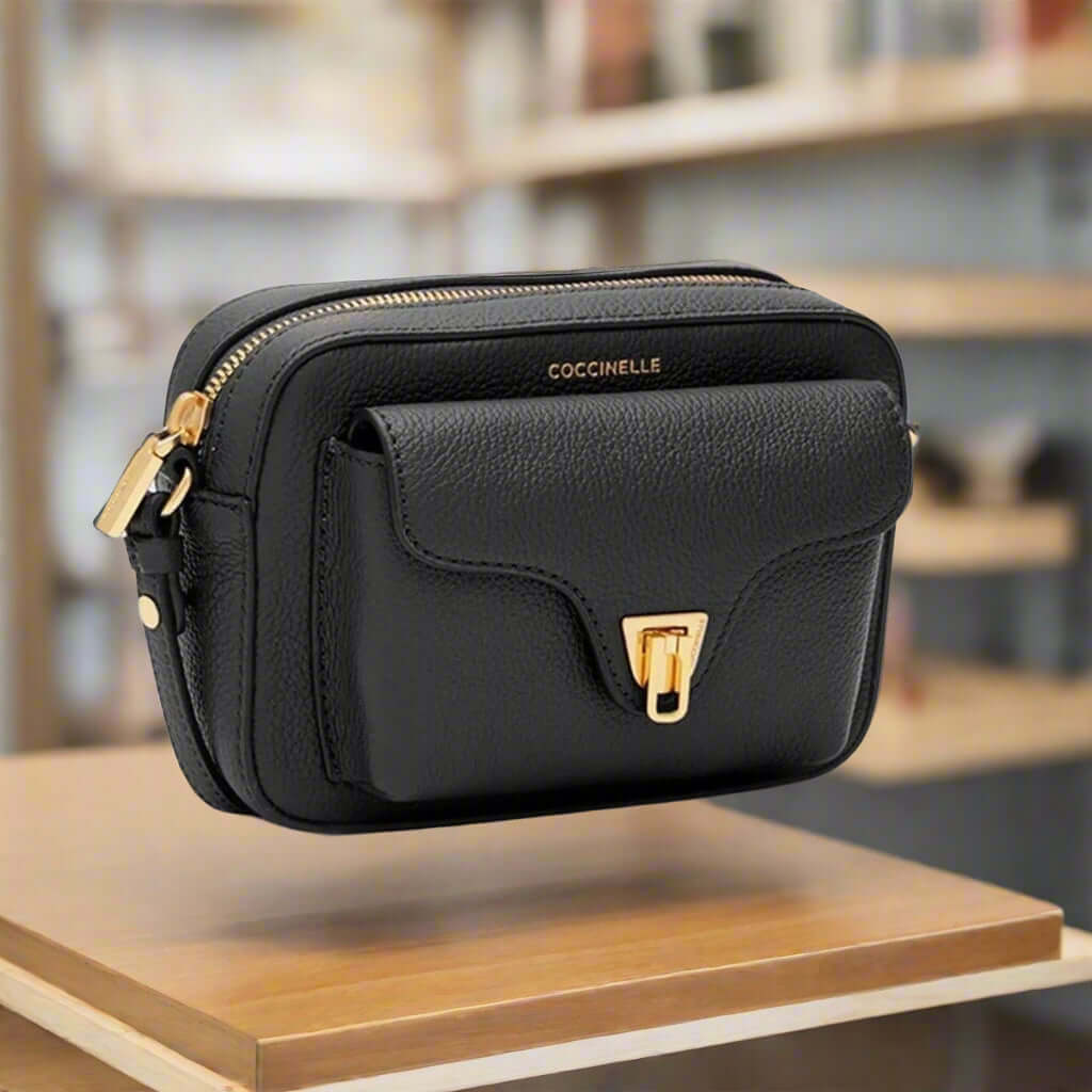 Black leather crossbody bag with gold accents on a white background