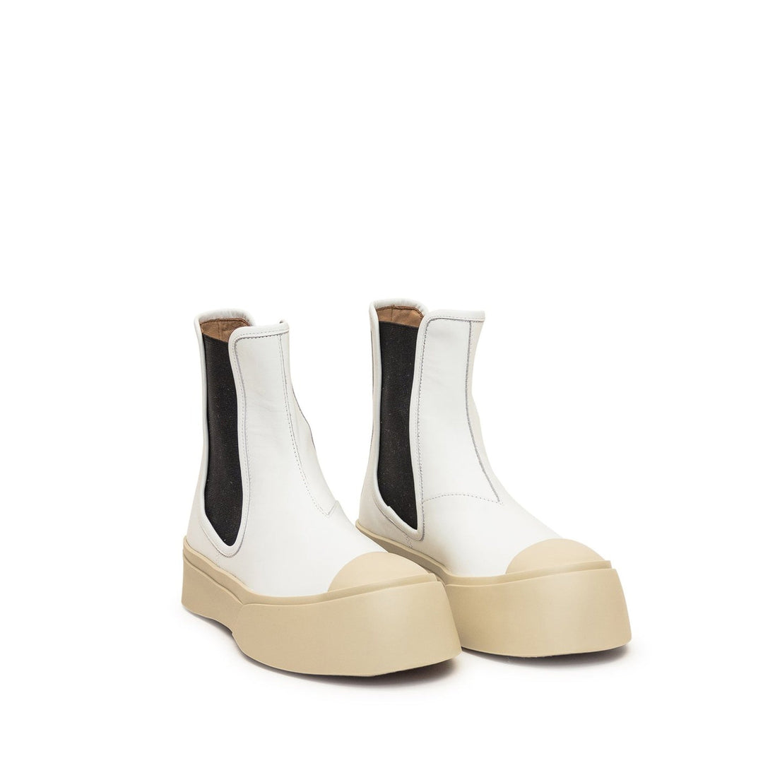 White Chelsea boots with beige soles on a white background