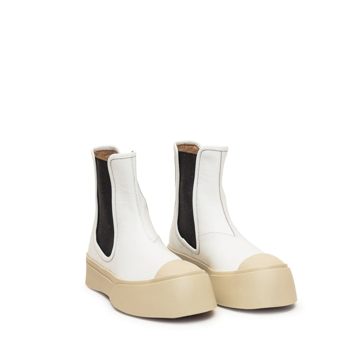 White Chelsea boots with beige soles on a white background