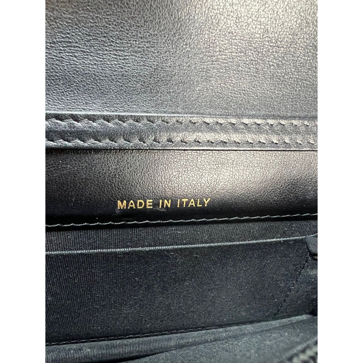 Inside view of a luxury bag showing 'MADE IN ITALY' inscription on a black leather interior.