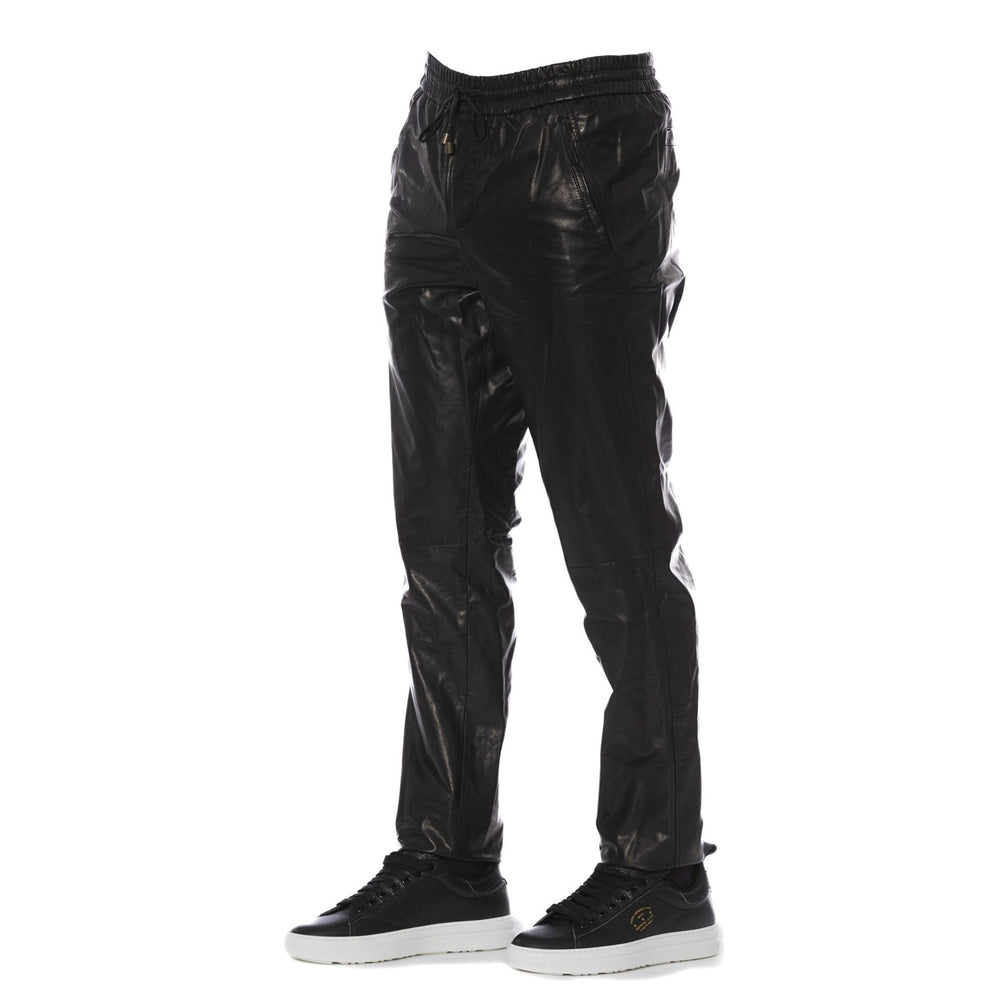 A pair of black Trussardi trousers with a visible logo, designed with two pockets, and a man standing in front wearing white sneakers.