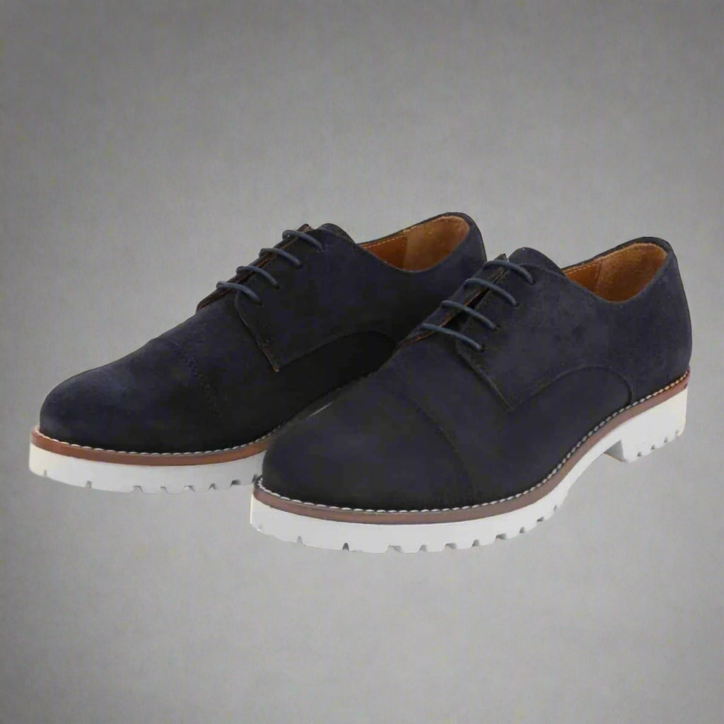 Pair of navy blue suede shoes with white soles on a light gray background