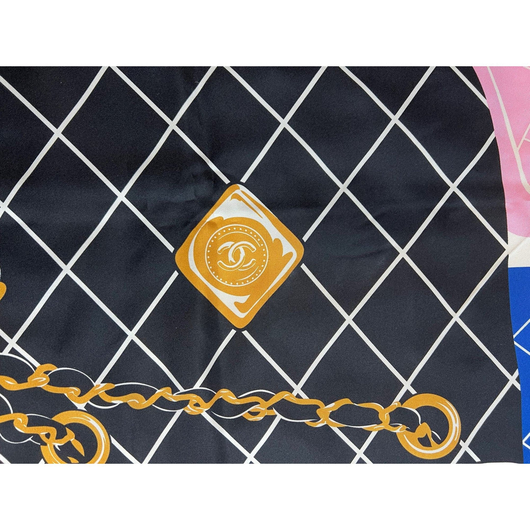 Close-up of a Chanel logo on a black and white checkered fabric with gold chain design.