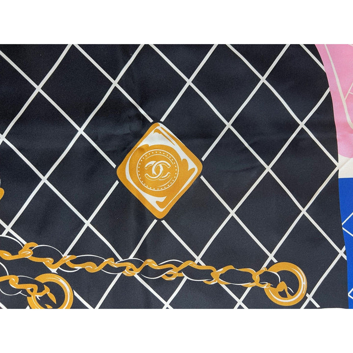 Close-up of a Chanel logo on a black and white checkered fabric with gold chain design.