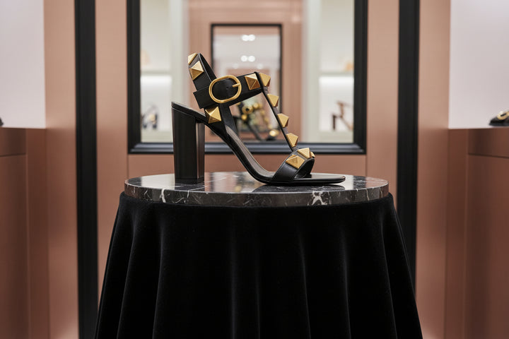 Black sandal with gold accents on a white background