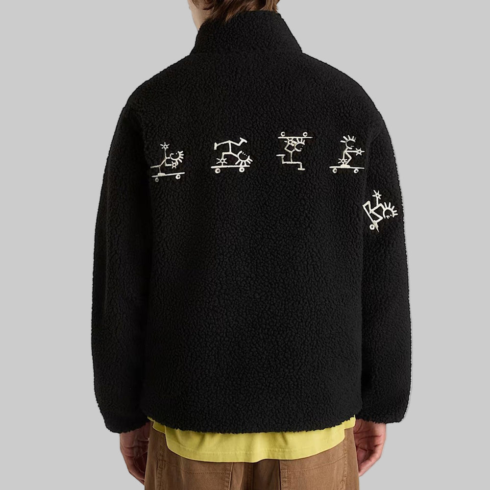 Black fleece jacket with white designs on the back, worn by a person.