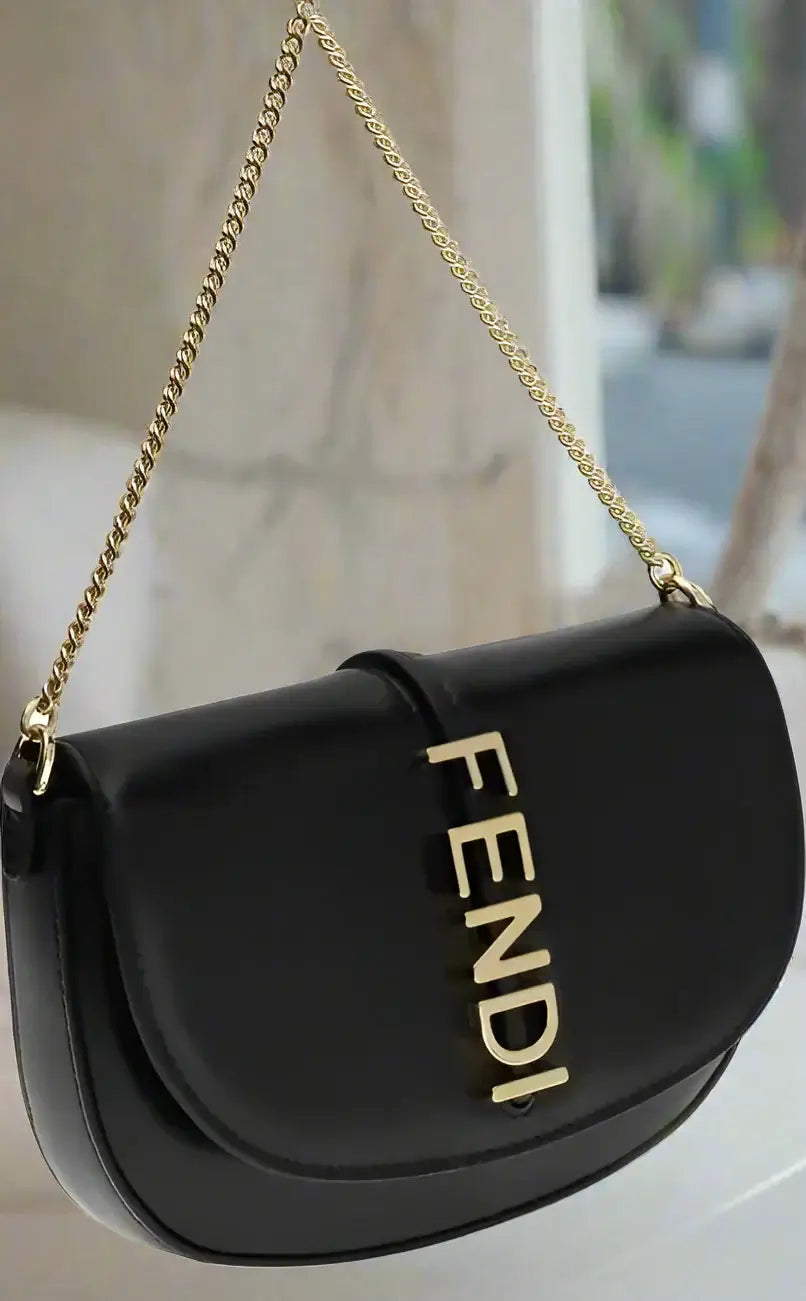 Black Fendi handbag with gold chain strap on a white background