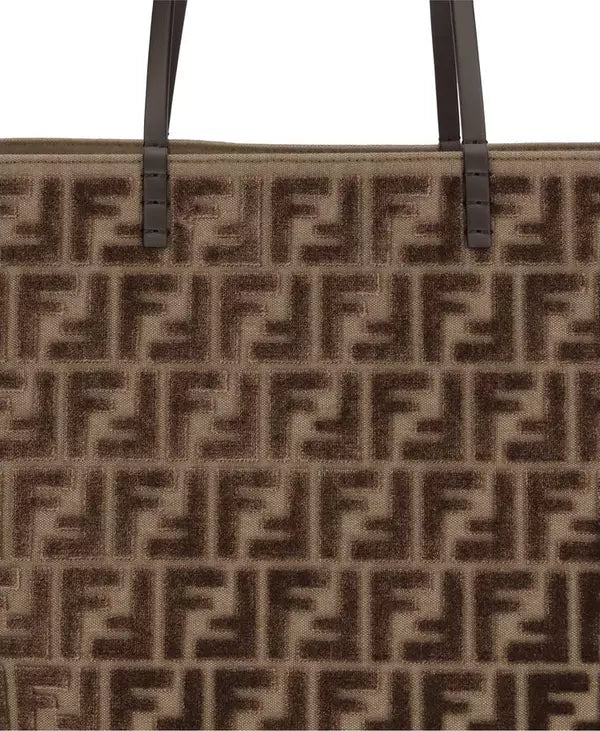 Close-up of a brown handbag with a prominent logo pattern on a white background