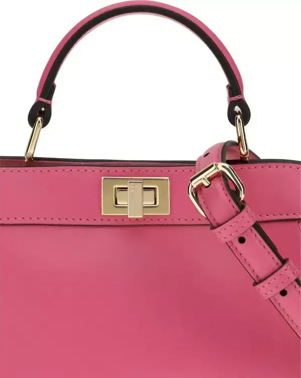 Close-up of a pink handbag with gold hardware on a white background