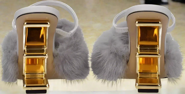 Pair of sandals with gold buckles and gray fuzzy straps on a white background
