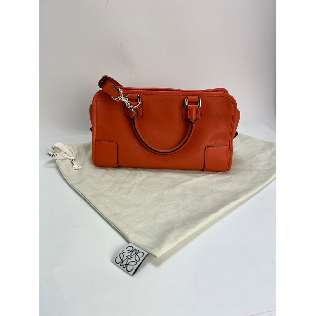Orange handbag on a white surface with a visible brand tag.