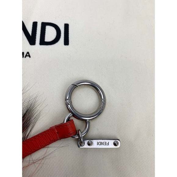 Fendi keychain with red strap and silver ring on a Fendi branded background