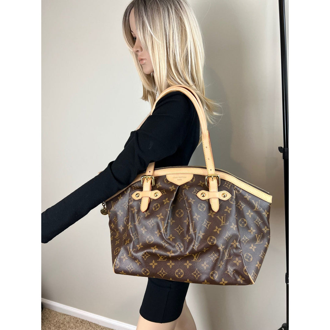 Person holding a brown patterned handbag with beige accents