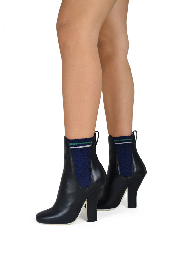 Black high-heeled boots with blue accents worn by a person on a white background