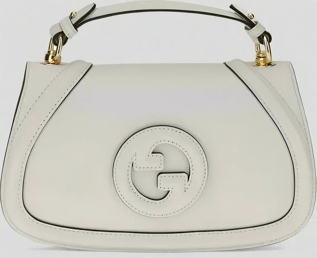White handbag with a gold handle on a white background