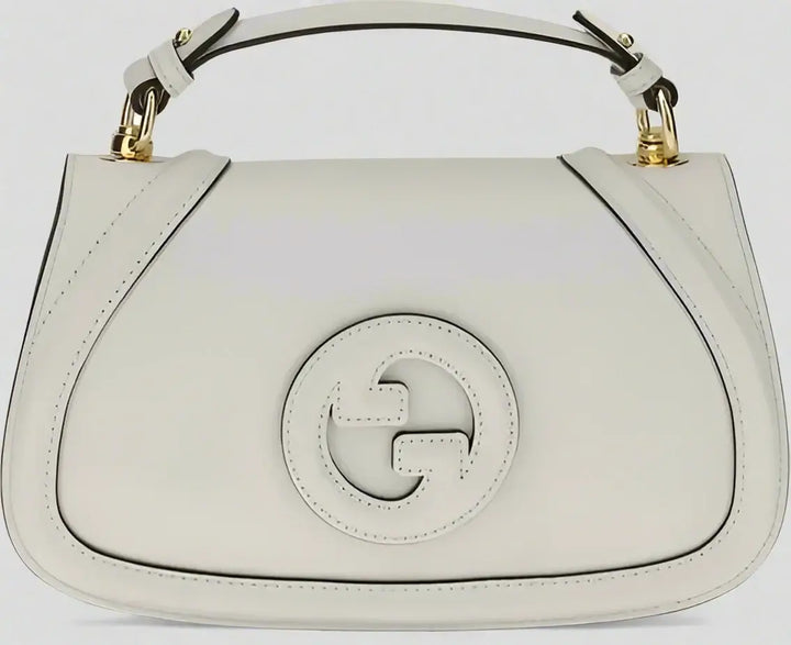 White handbag with a gold handle on a white background