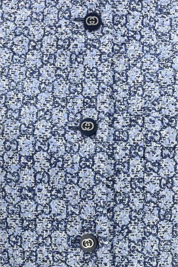 Close-up of a textured blue fabric with Gucci logo buttons.