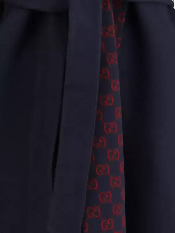 Navy blue suit with a red and black patterned tie on a dark background