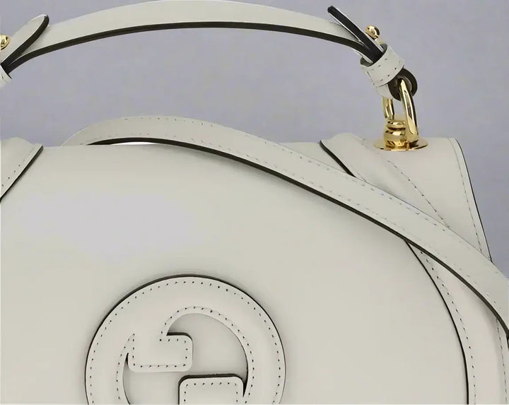 White handbag with gold accents on a white background