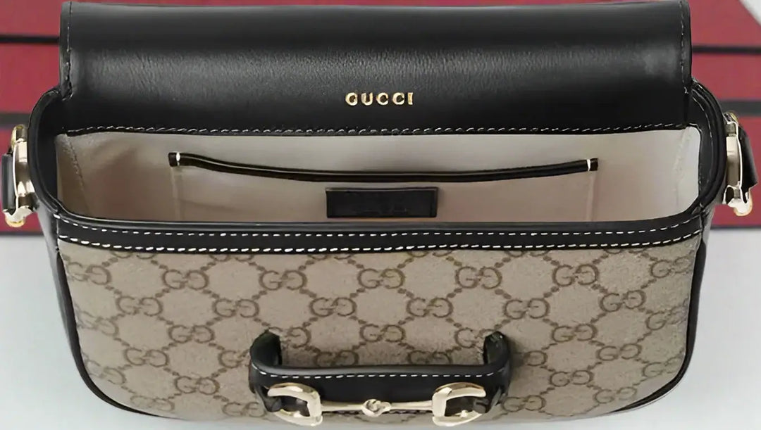 Gucci handbag with monogram pattern and black leather top, on a white background