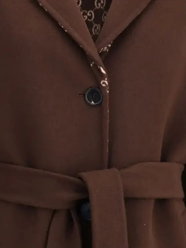 Close-up of a brown coat with a button and part of a patterned fabric visible.