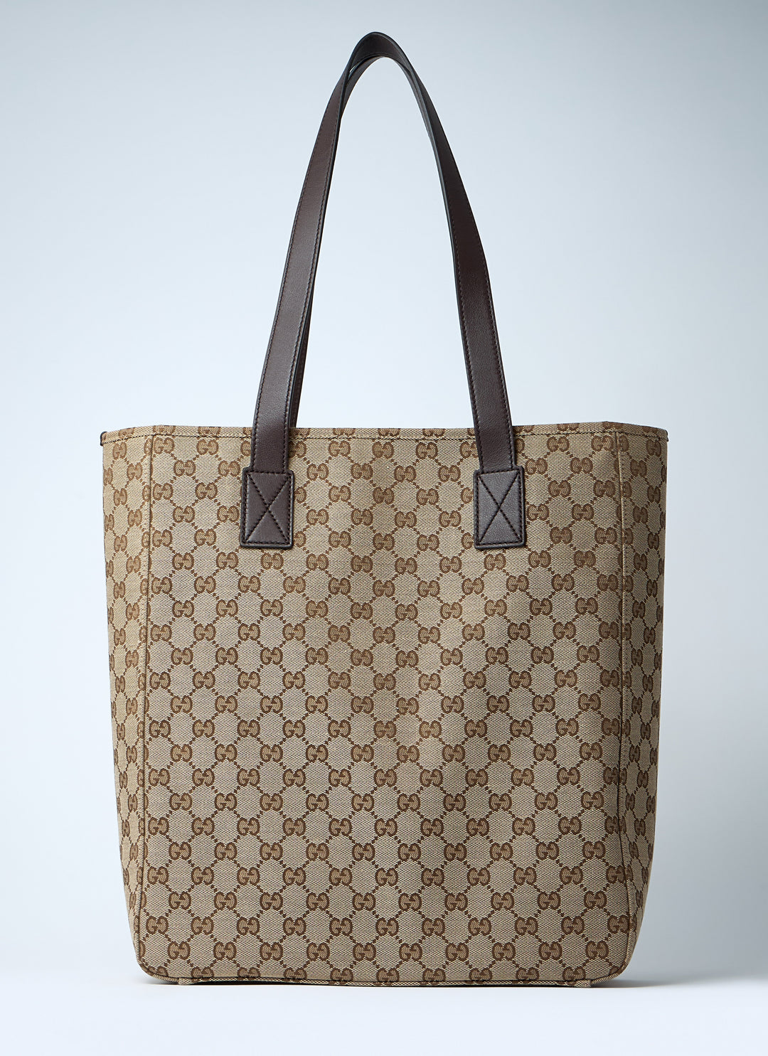 Beige tote bag with brown pattern and black handles on a light gray background