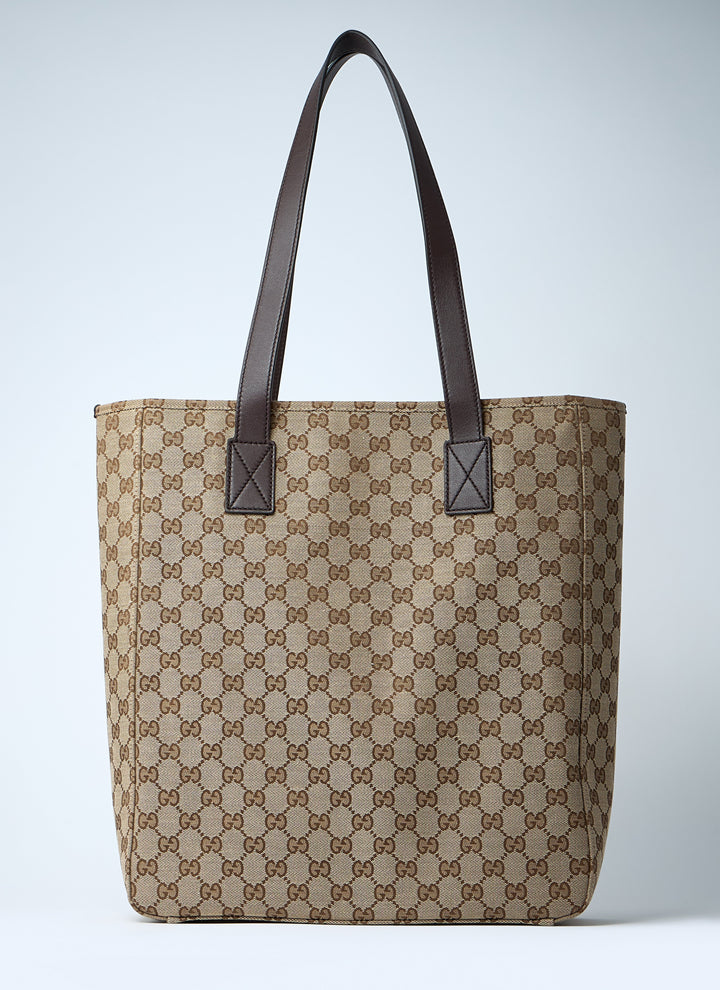 Beige tote bag with brown pattern and black handles on a light gray background