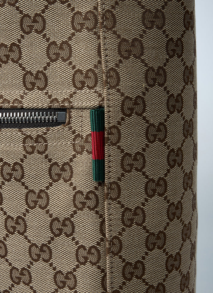 Close-up of a Gucci suitcase with monogram pattern and zipper detail.