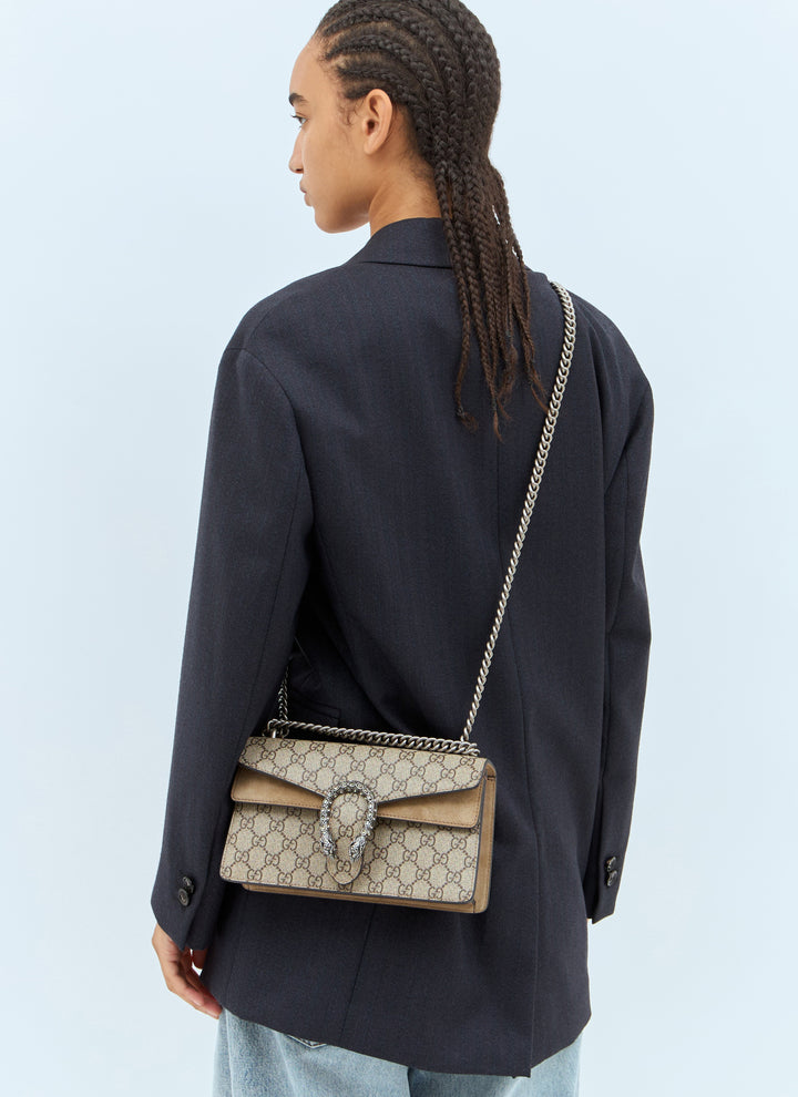 Person wearing a black jacket with a Gucci handbag on a light blue background