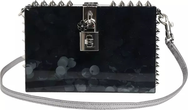Black studded handbag with a strap on a blurred background